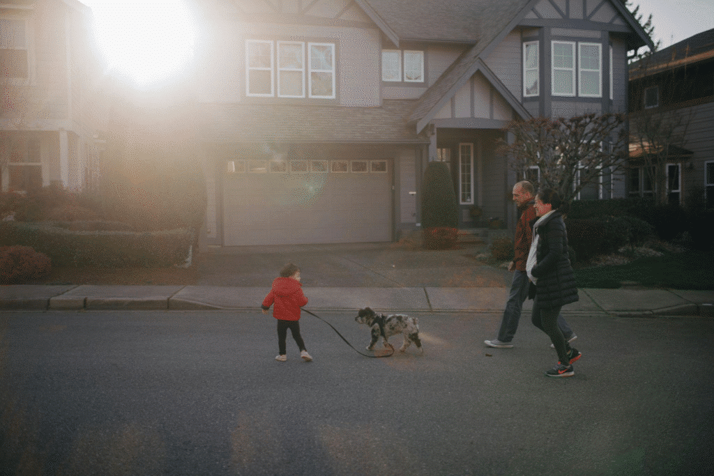 Parents walking with a child and a dog near a residential street
